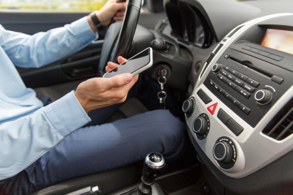 Driver holding mobile phone while driving his car